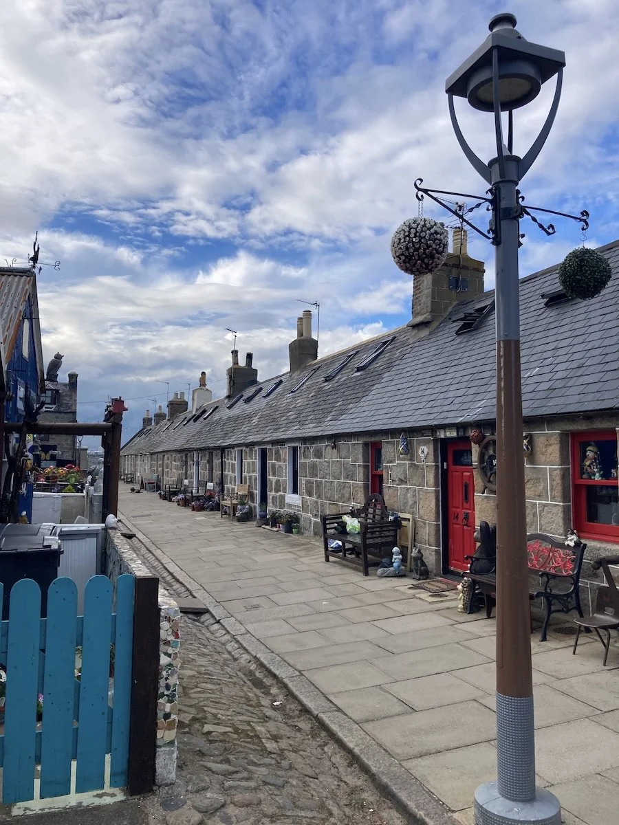 Pedestrian paved street lined by one-storey houses on sunny day