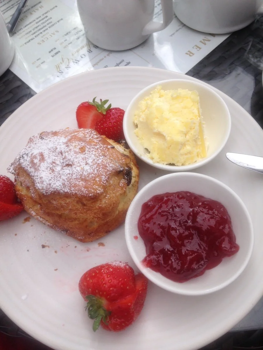 Jam, strawberries, a scone and cream on a plate