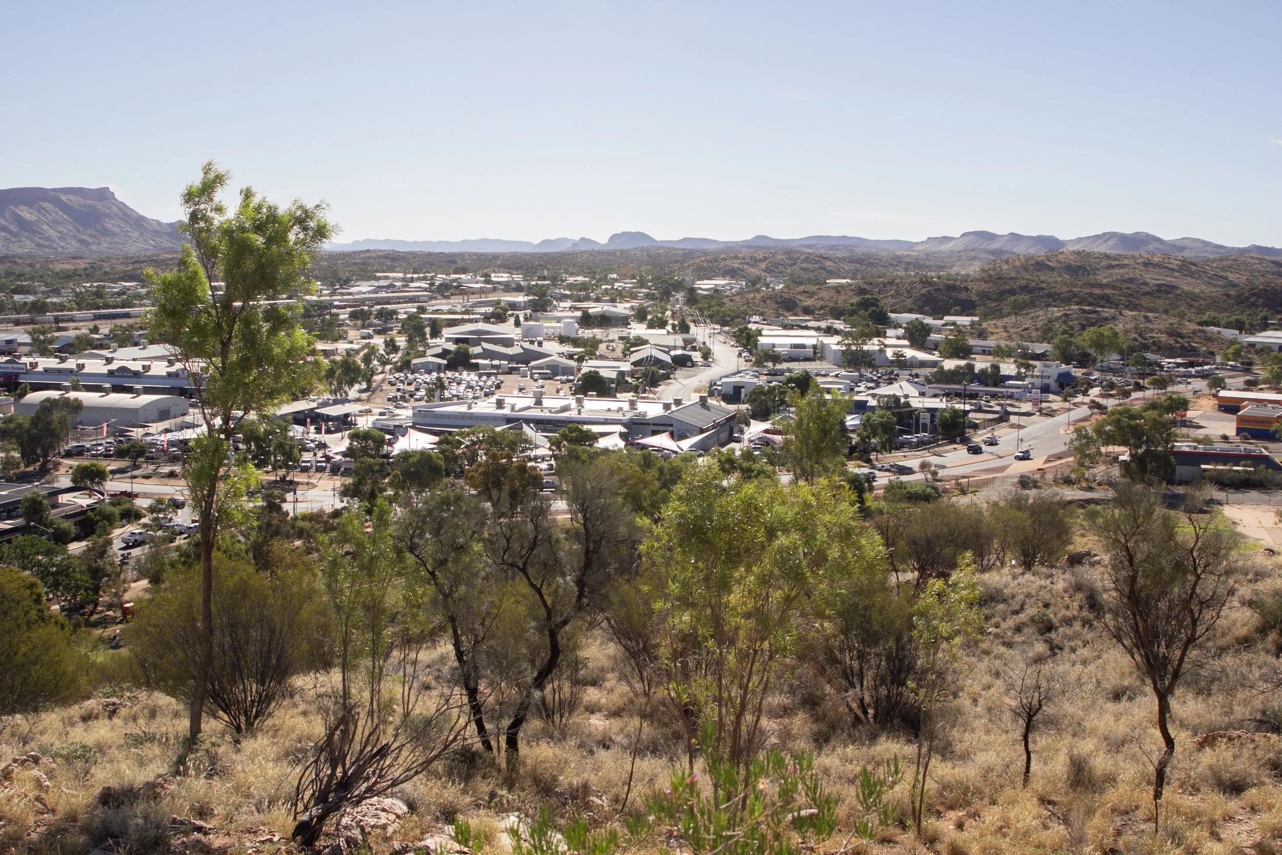 View from hillside onto low-rise town with hills in background