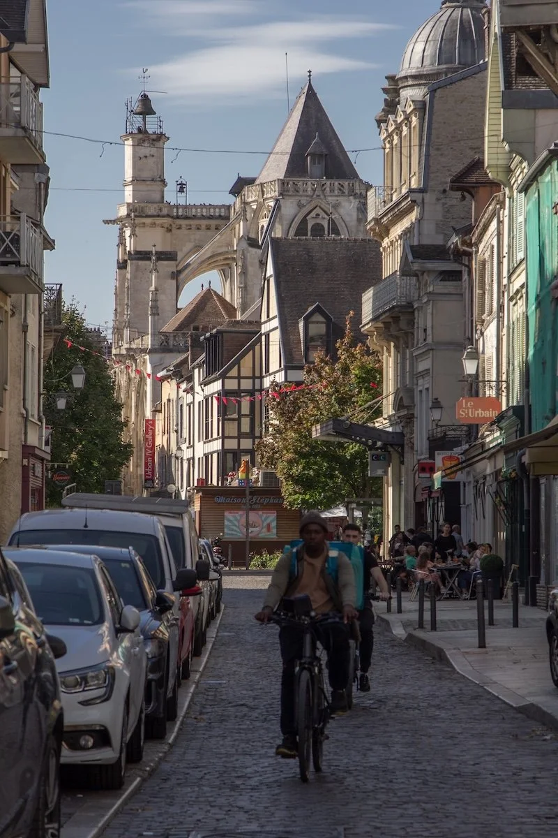 Man cycling down cobbled street with gothic church in background