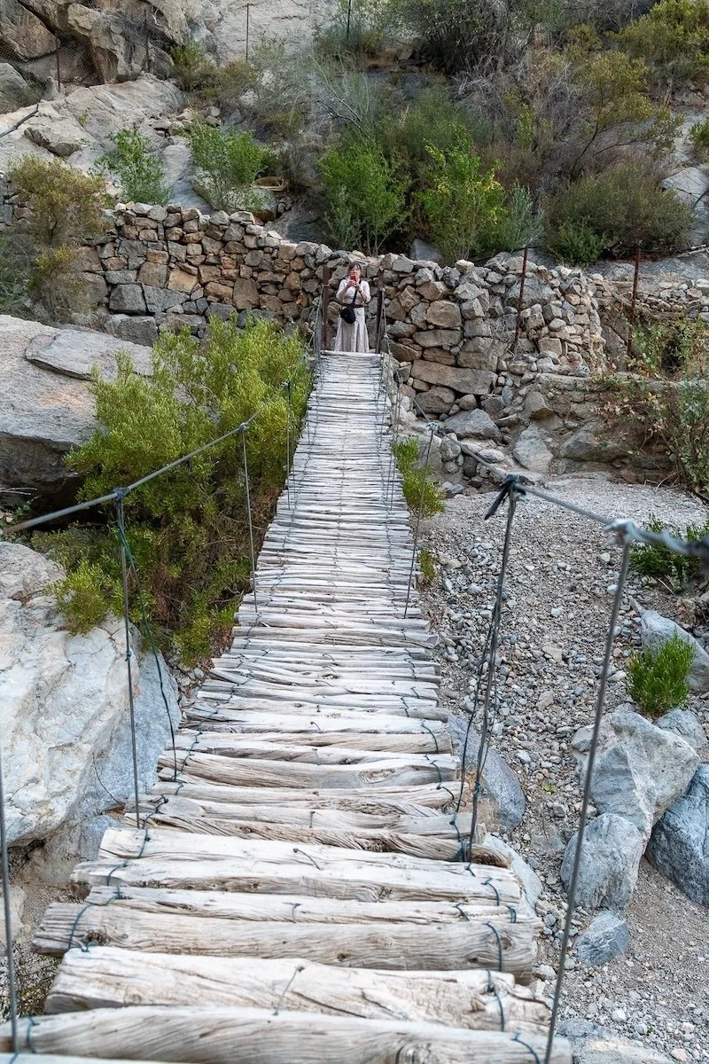 Wooden pedestrian suspension bridge and woman standing at far end