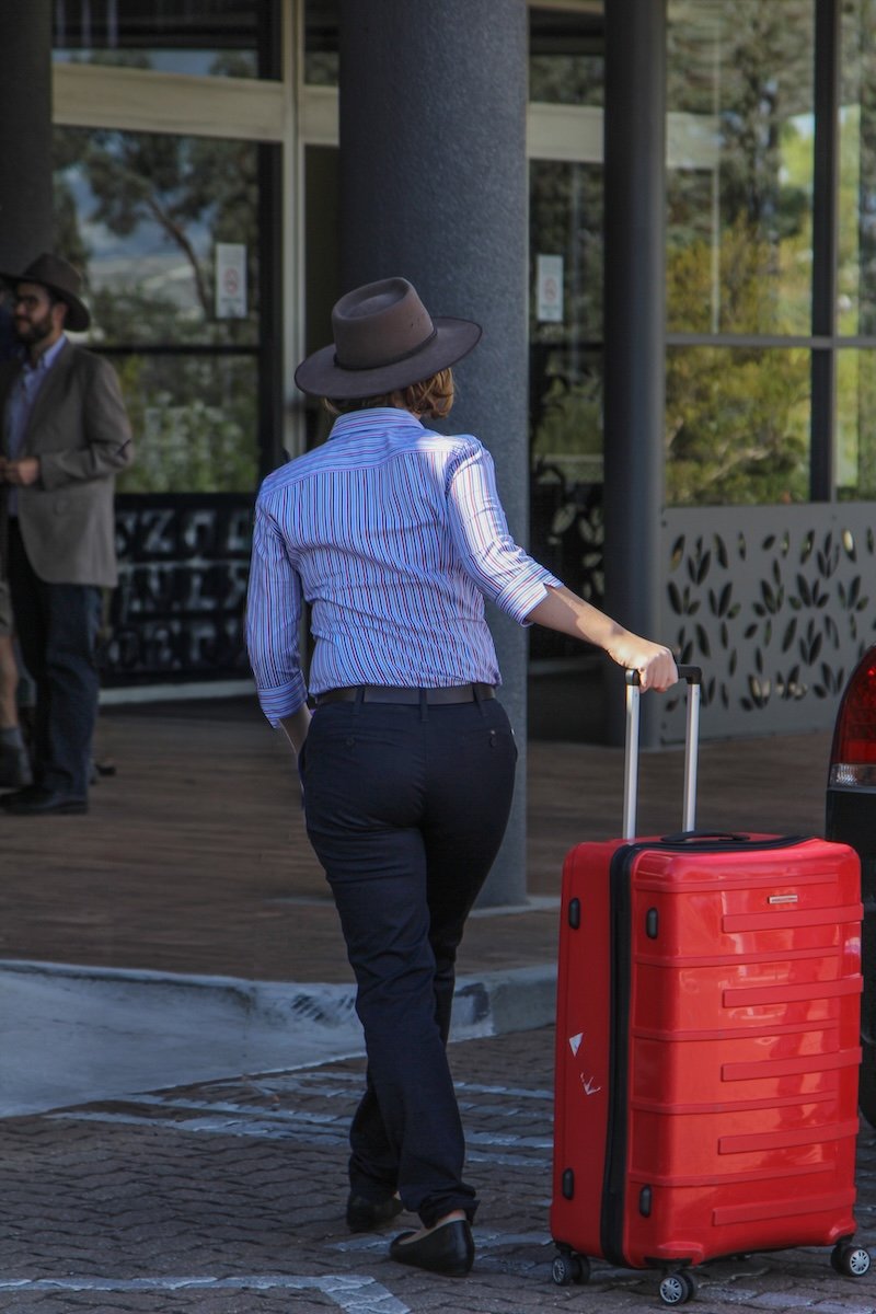 Woman seen from behind with large red suitcase