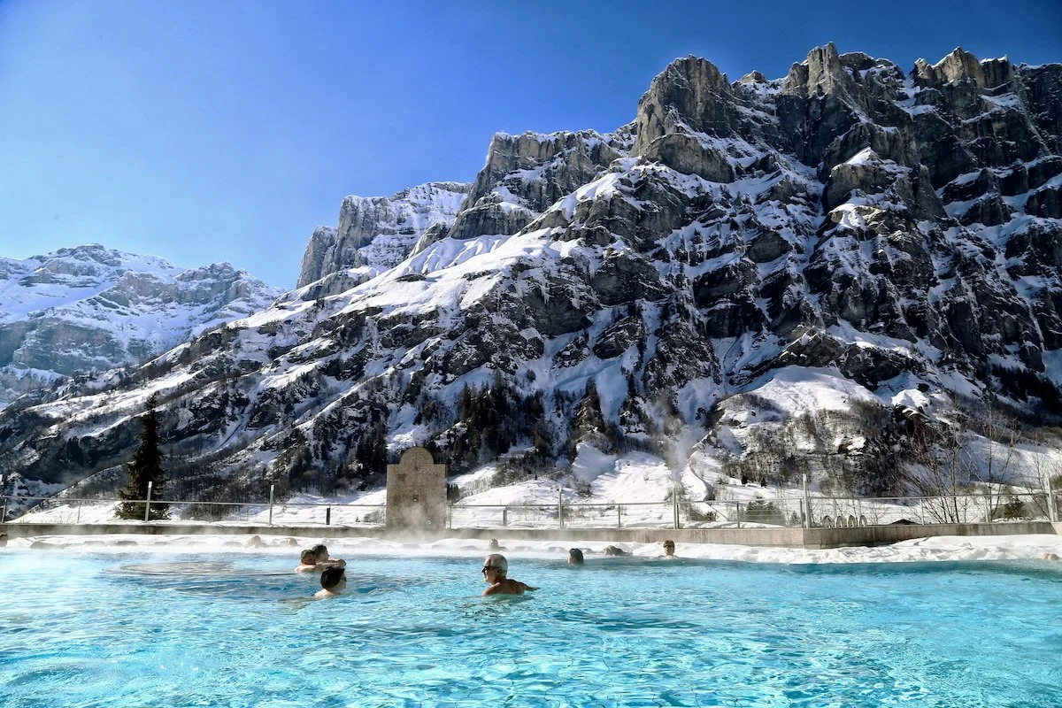 six people in thermal pool in winter mountain landscape