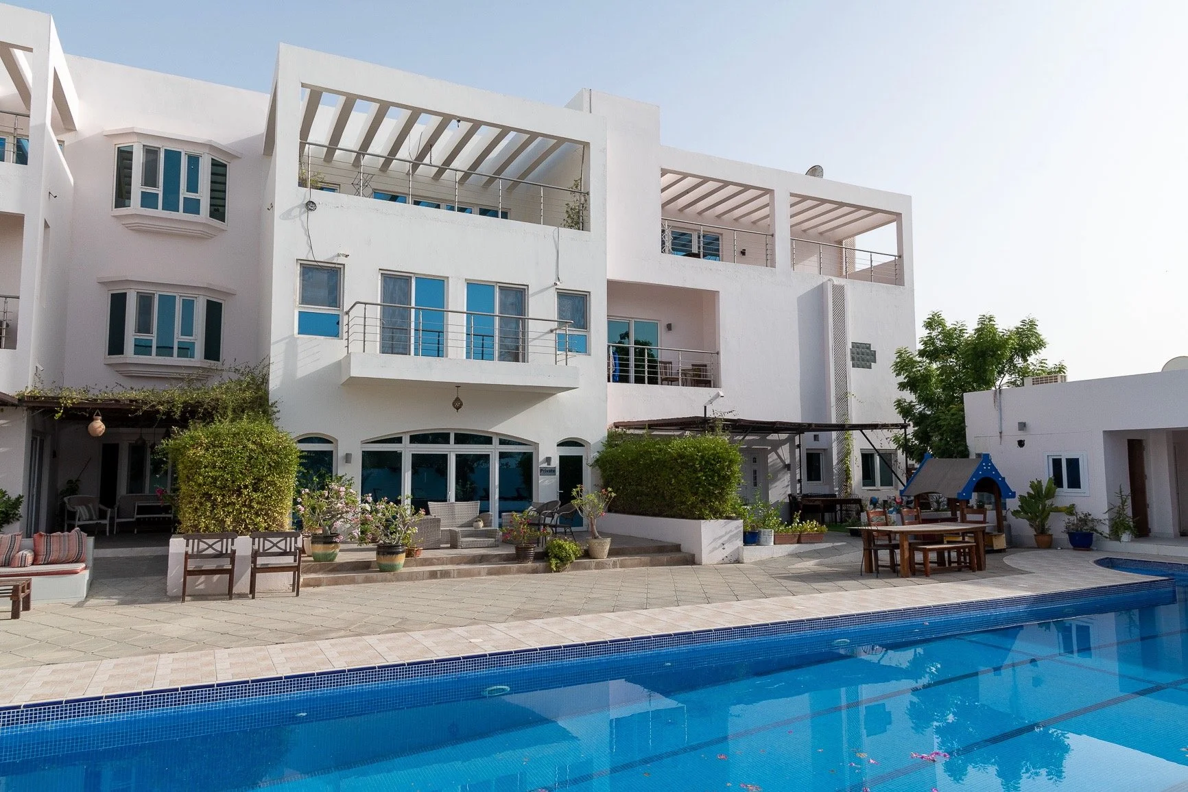 Two-storey white building overlooking blue swimming pool