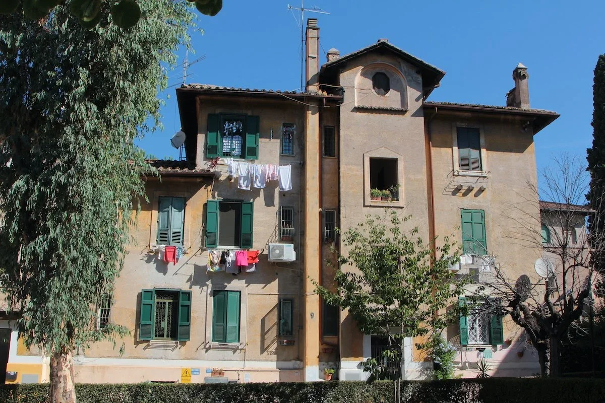 Three storey building with green shutters and washing drying at windows