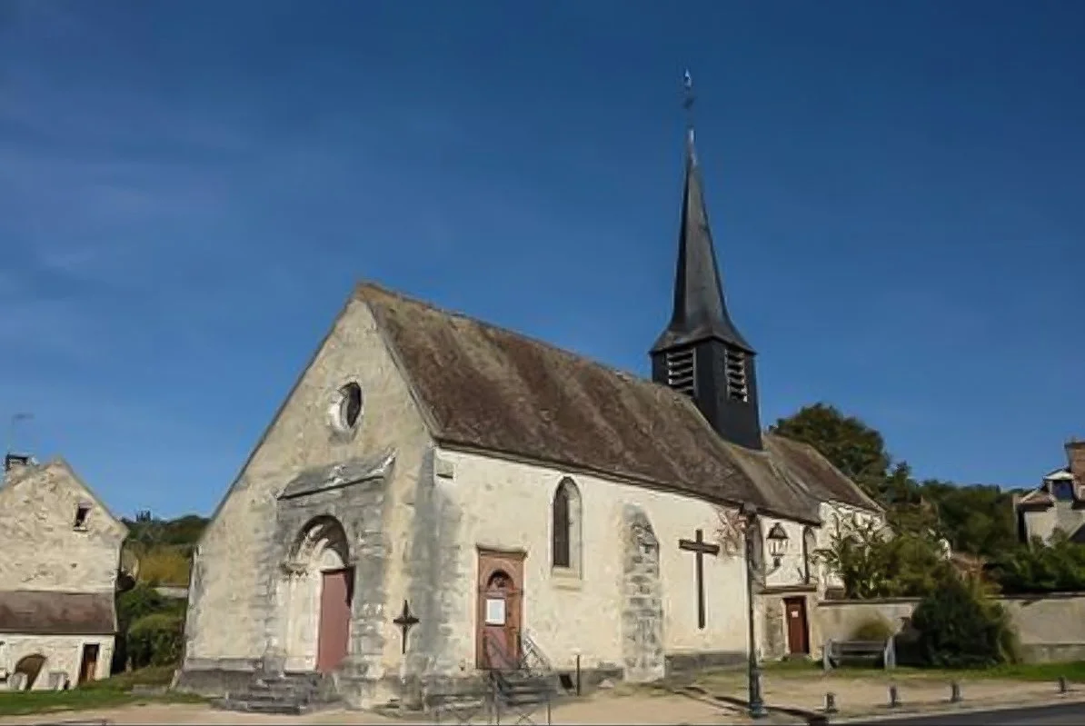 Small Romensque church with pointed spire against blue sky