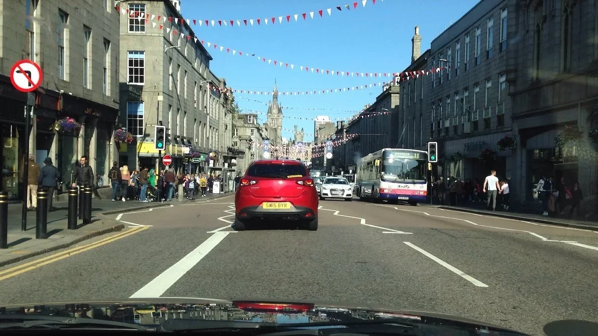 Street seen through windscreen with red car and bunting