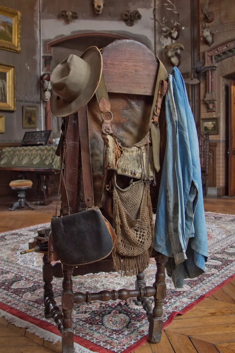 Back of chair with hat, bag and blue overall hanging off it