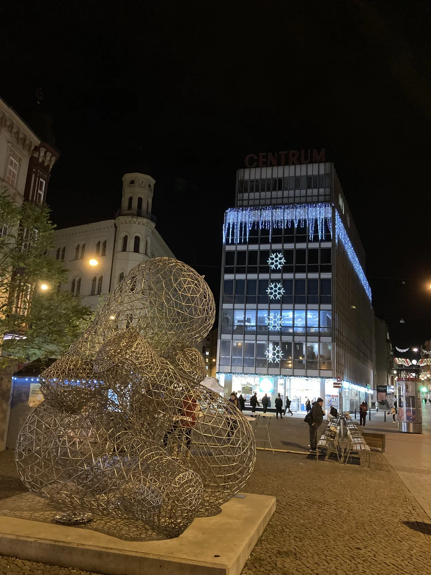 Gold filigree statue and building with snowflakes  at night