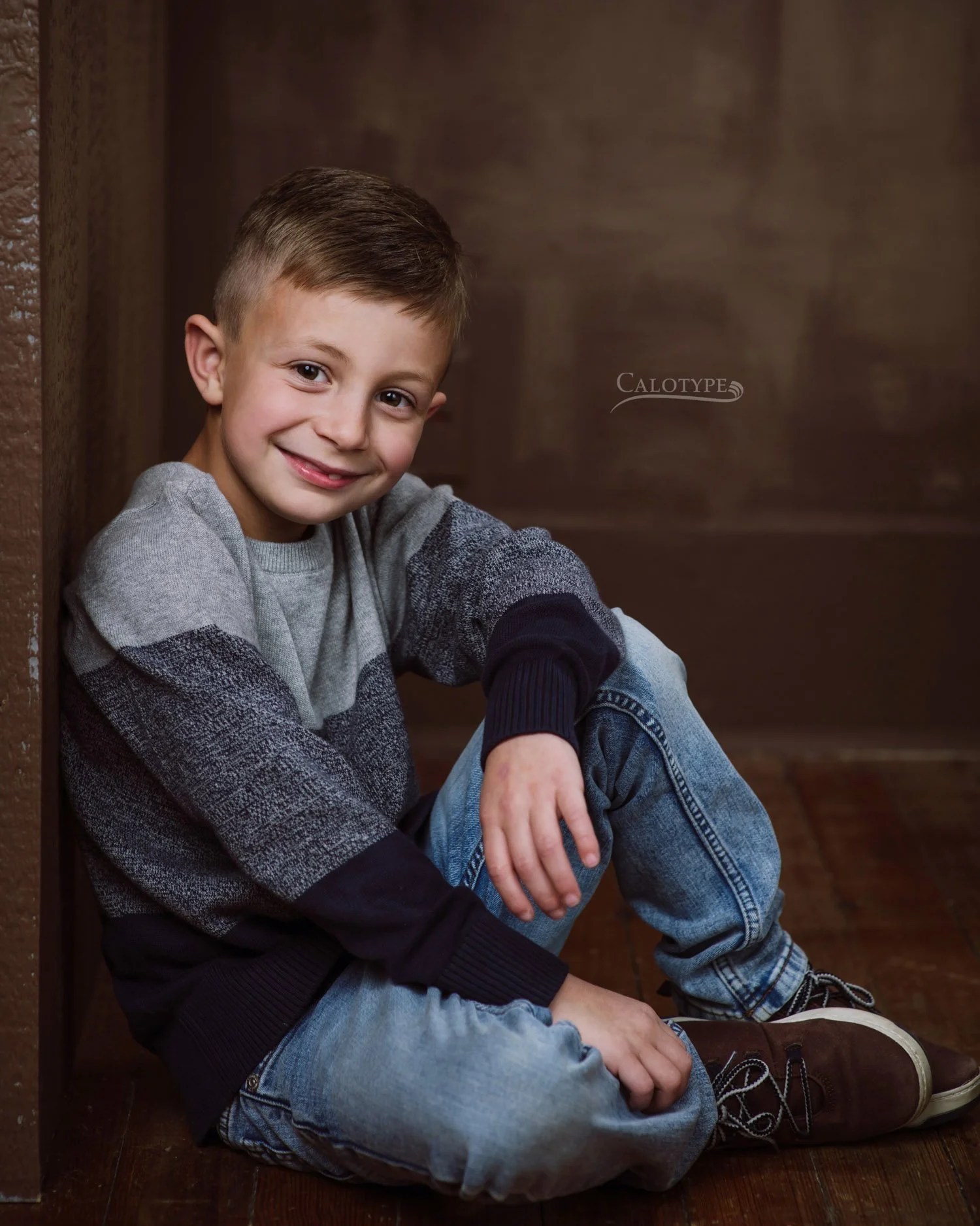six year old boy posing on floor, smiling