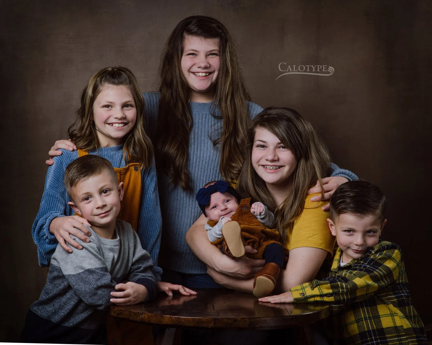 group photo of six cousins, smiling, ranging from newborn to 13