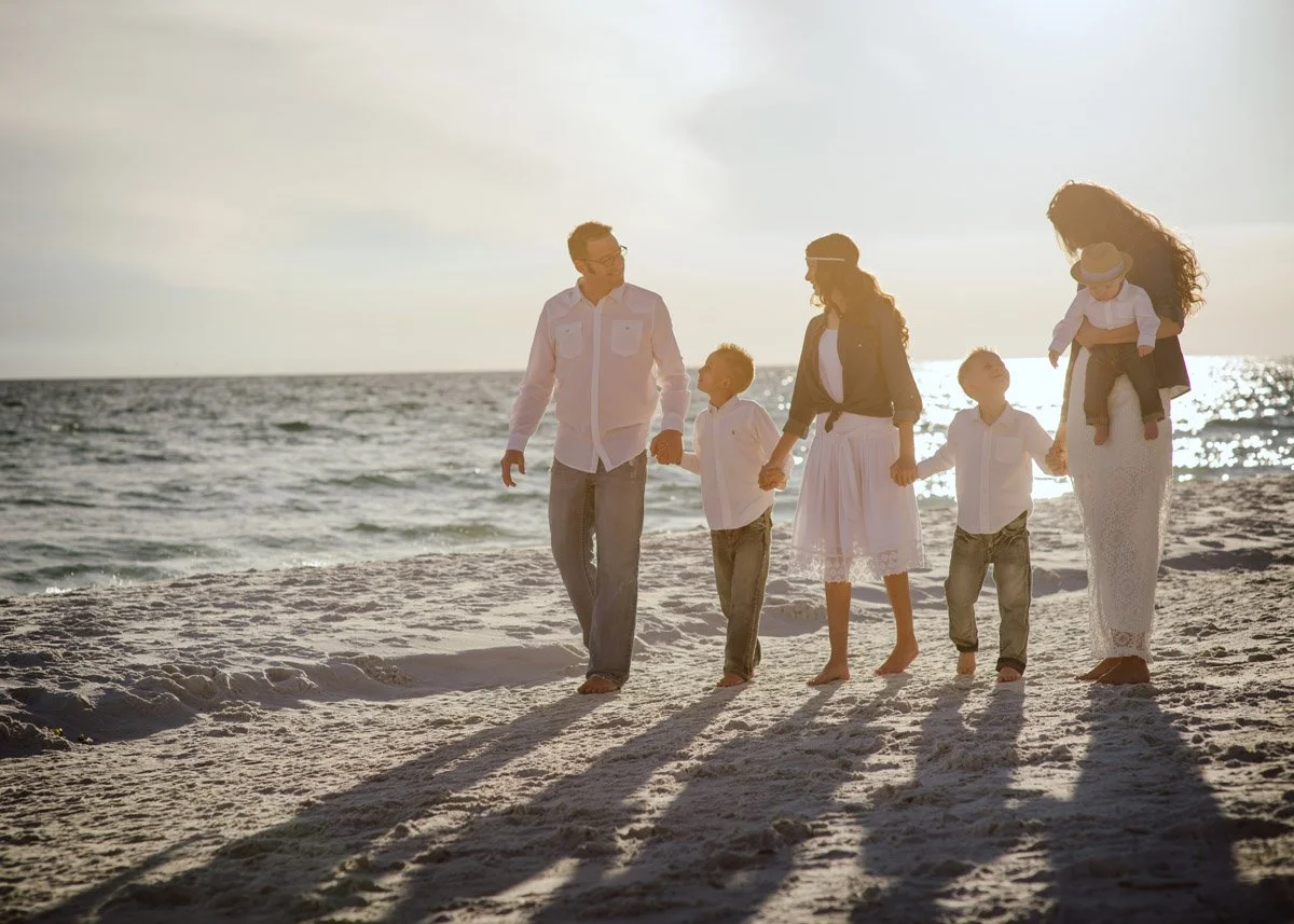 Horizontal pictures of mom, dad and four children walking on white beach in Destin for a family picture