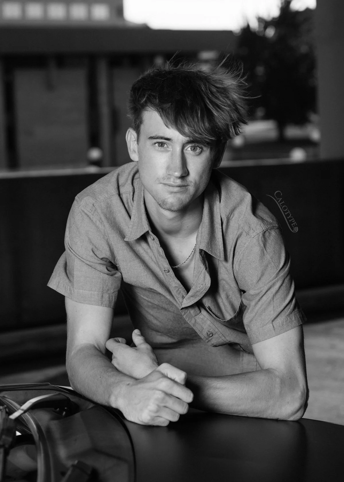 black and white photo of a high school senior guy leaning on his car