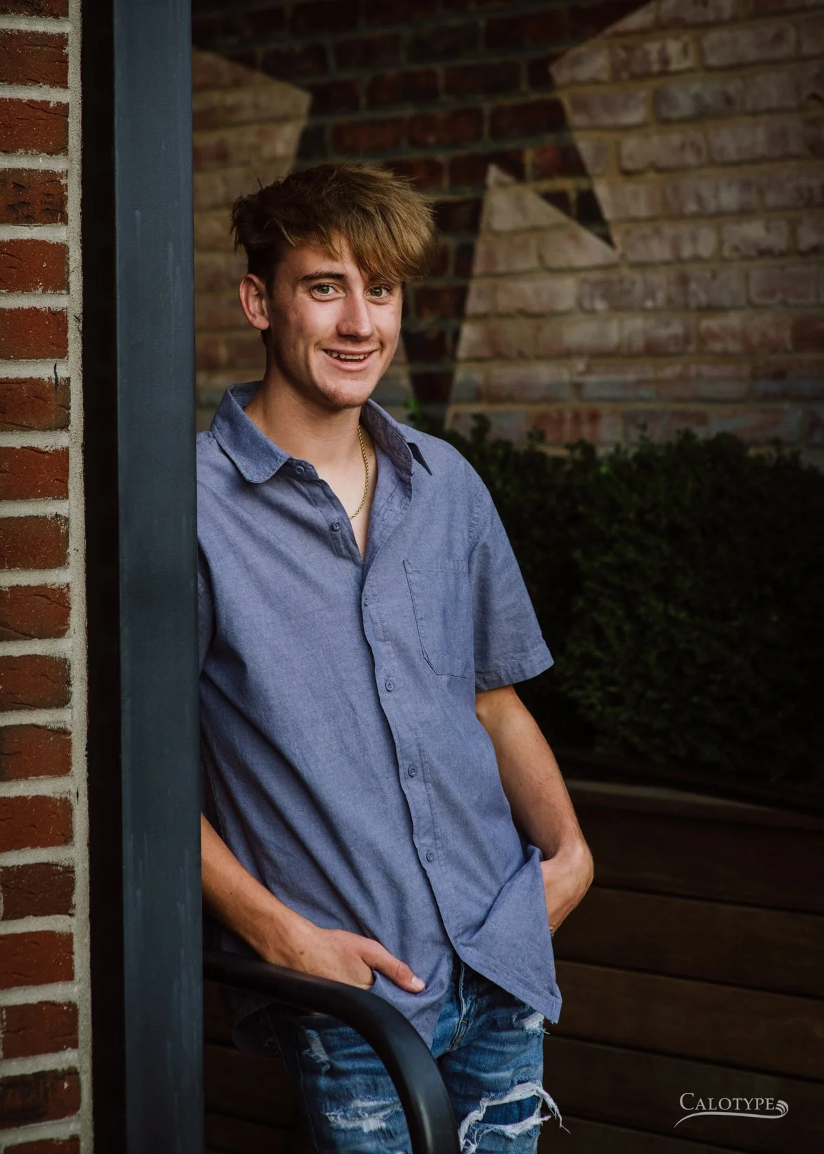 smiling senior boy leaning against wall for senior pictures