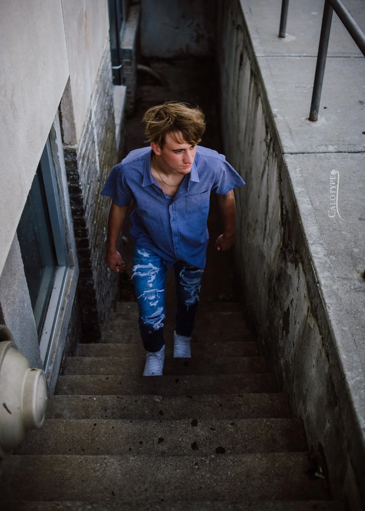 senior boy walking up stairs in downtown Springfield for a senior photoshoot