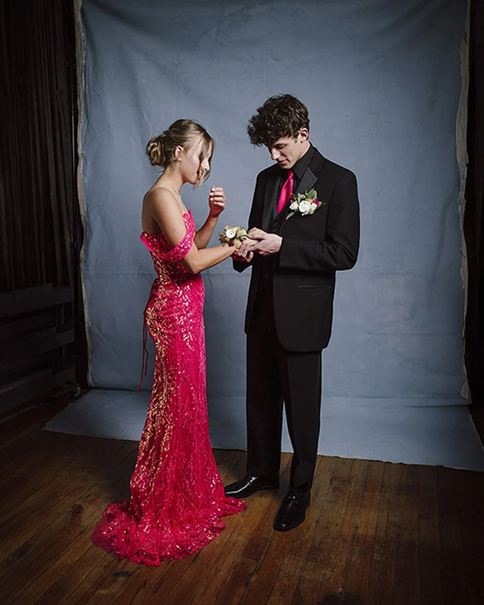Two high school seniors in formal wear being professionally photographed inside the Calotype studio in Neosho, MO