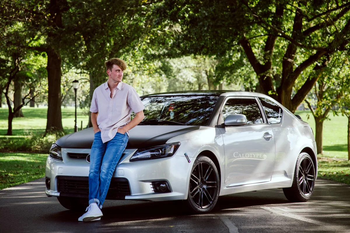 senior boy leaning on his car for senior pictures