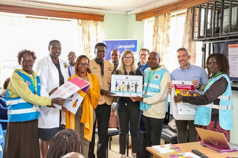 Eleven people holding breast cancer education material