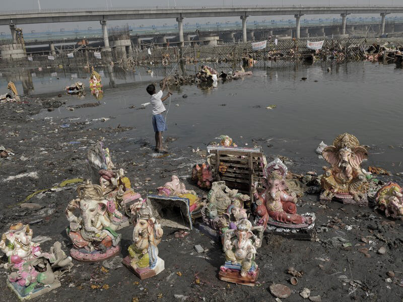  Child playing on the banks of Yamuna, surrounded by post immersion effects 