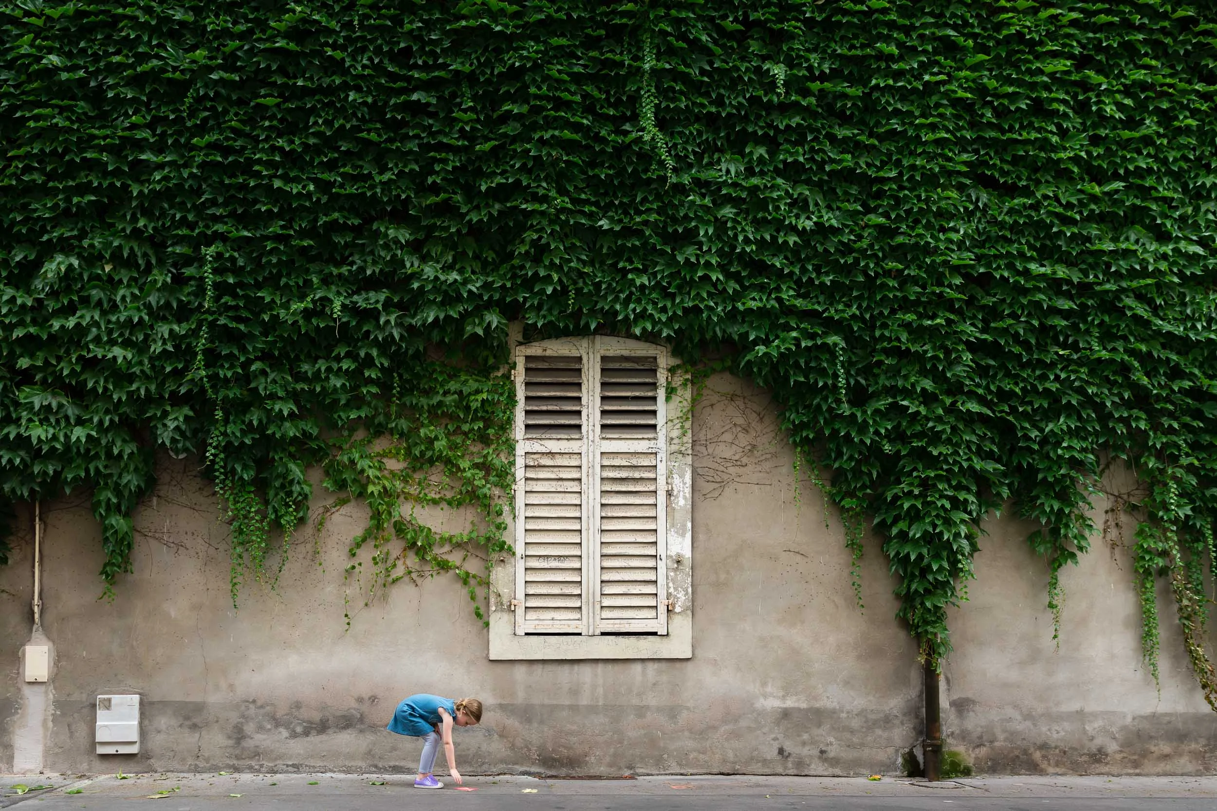 girl_picking_up_flyer_under_ivy_and_white_shutters_in_france_Personal_portfolio_by_rebecca_hunnicutt_farren.jpg