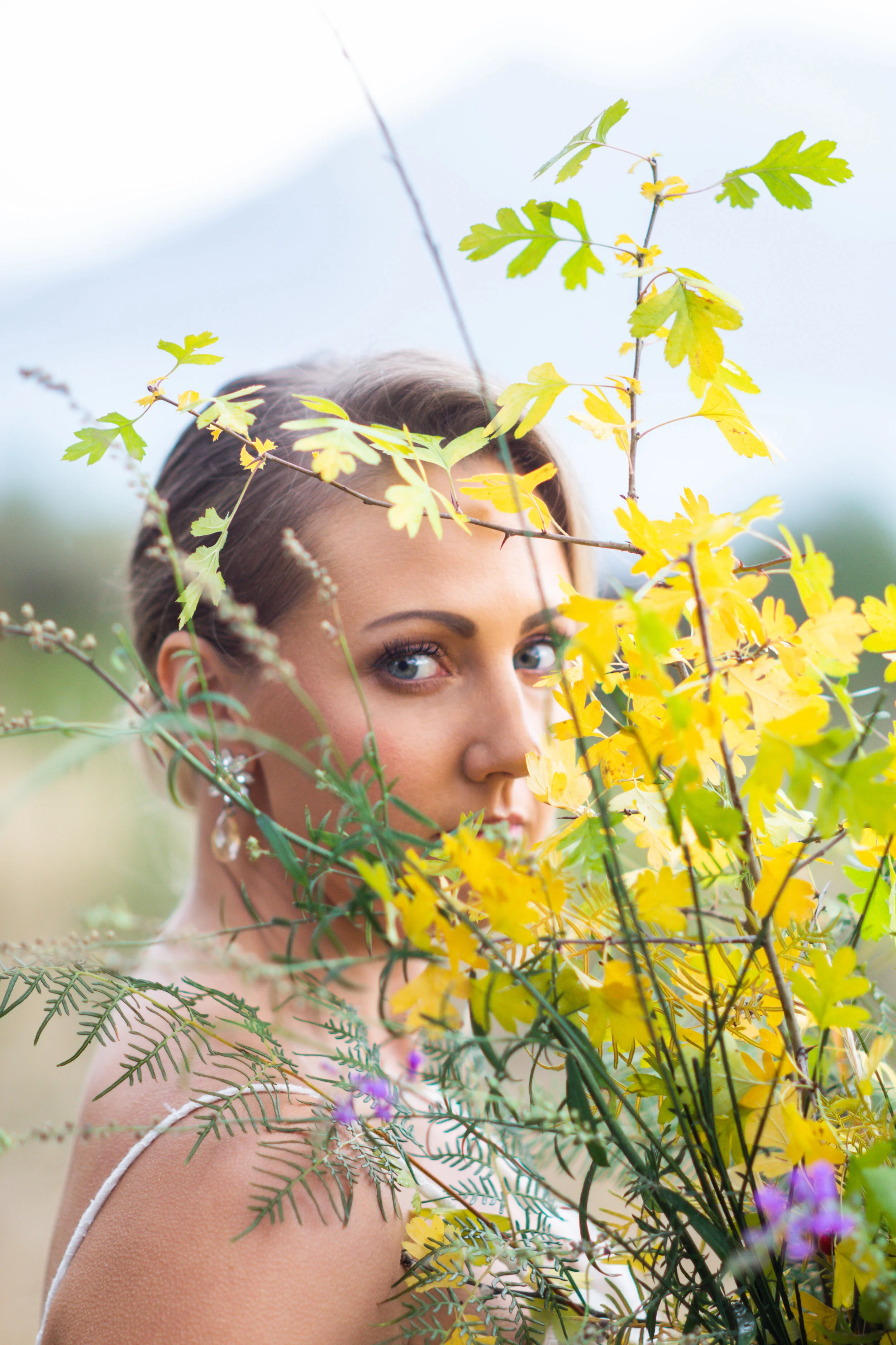 Model looking through autumn bouquet of greenery, editorial, portrait