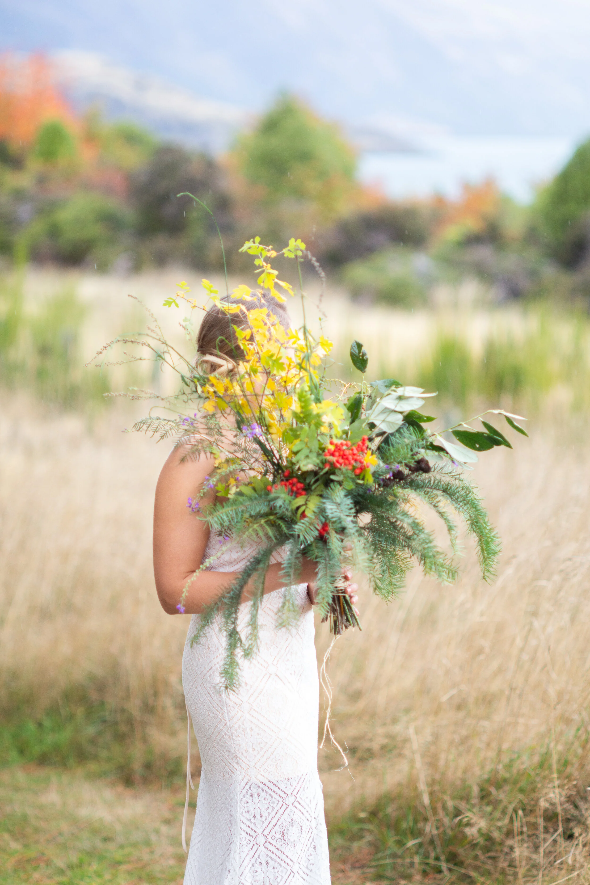 Model holding autumn greenery bouquet amongst grasses and mountains Queenstown