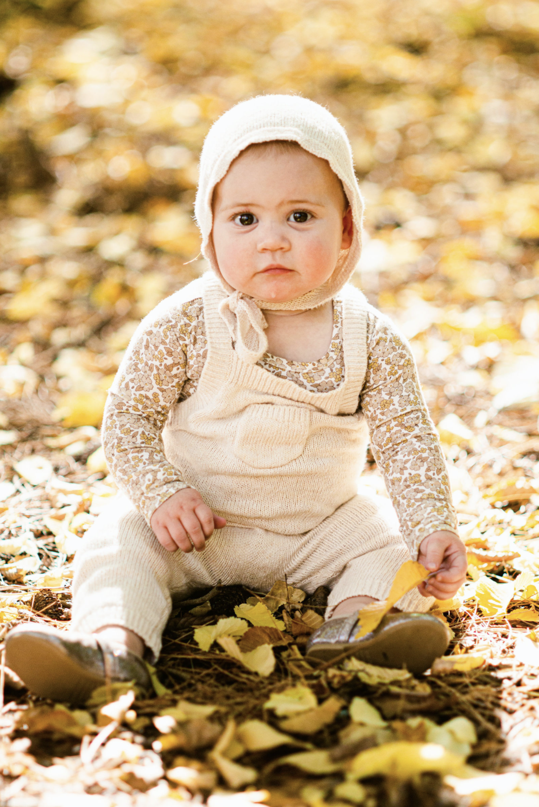 Baby sitting in autumn leaves for photo in Arrowtown