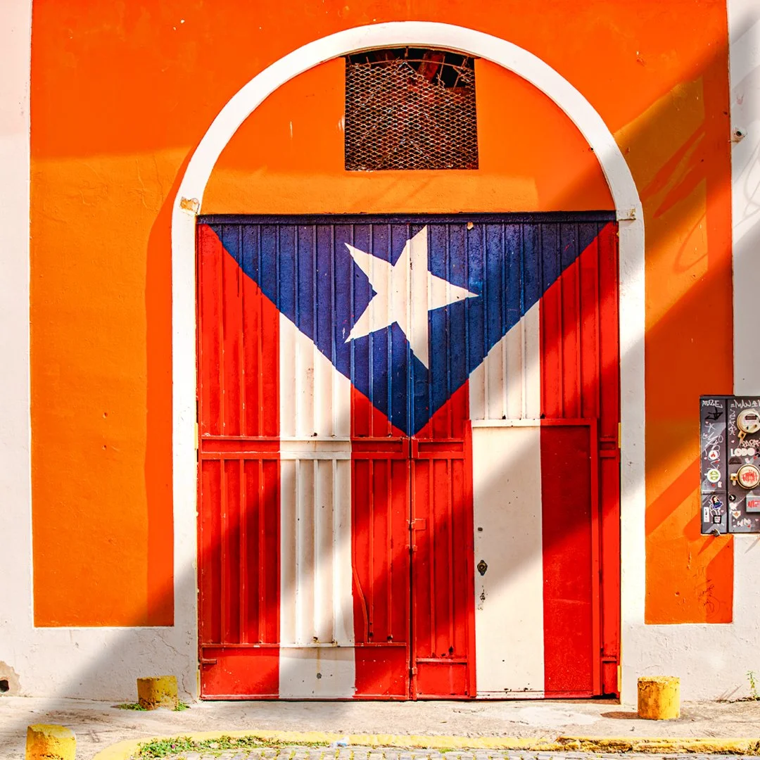 Colorful door painted with the Puerto Rican flag, set in an orange wall.
