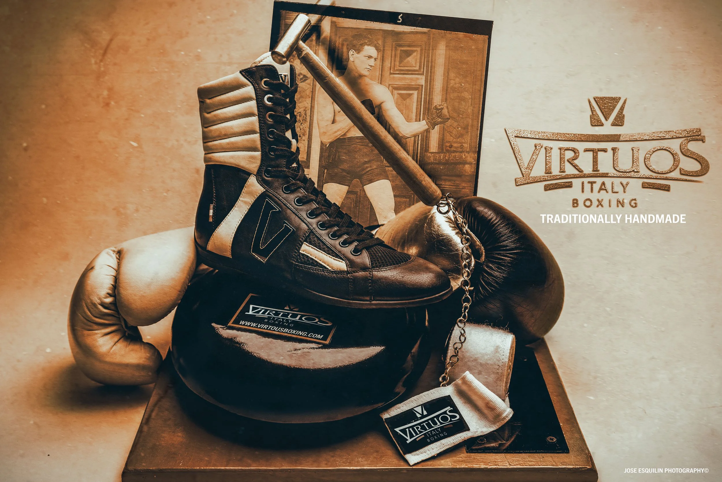A vintage boxing shoe, boxing gloves, and a boxing glove display with a vintage photograph of a boxer in the background. The display features a Virtuos Italy Boxing logo and website.