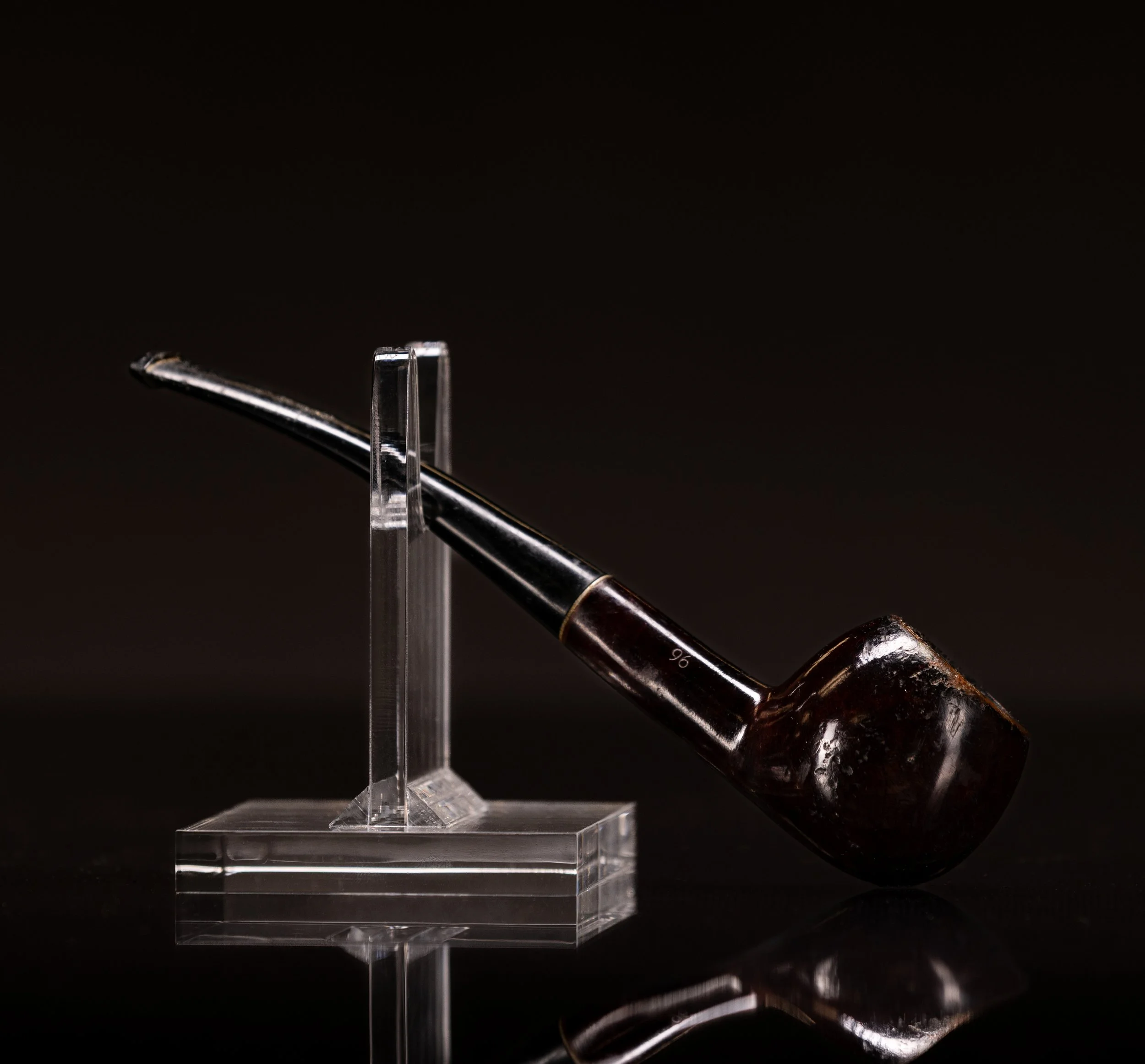 Close-up of a metal dental instrument resting on a clear acrylic stand against a black background.