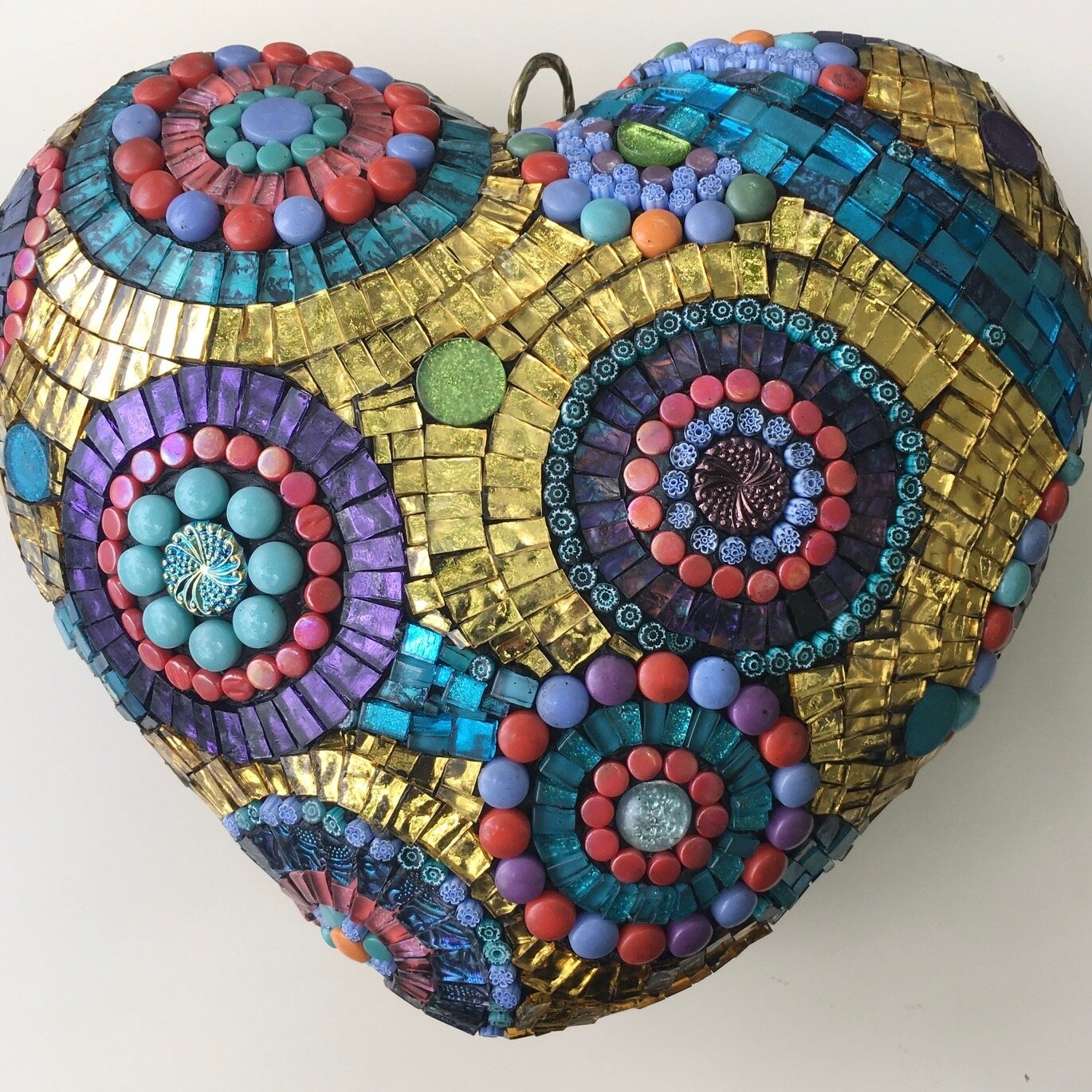 This 3D mosaic heart can be hung inside or out. The base is styrofoam covered with three layers of mesh and thinset. I used GE silicon window and door gel for the adhesive, then grouted with sanded grout. I applied three layers of sealant. These mate