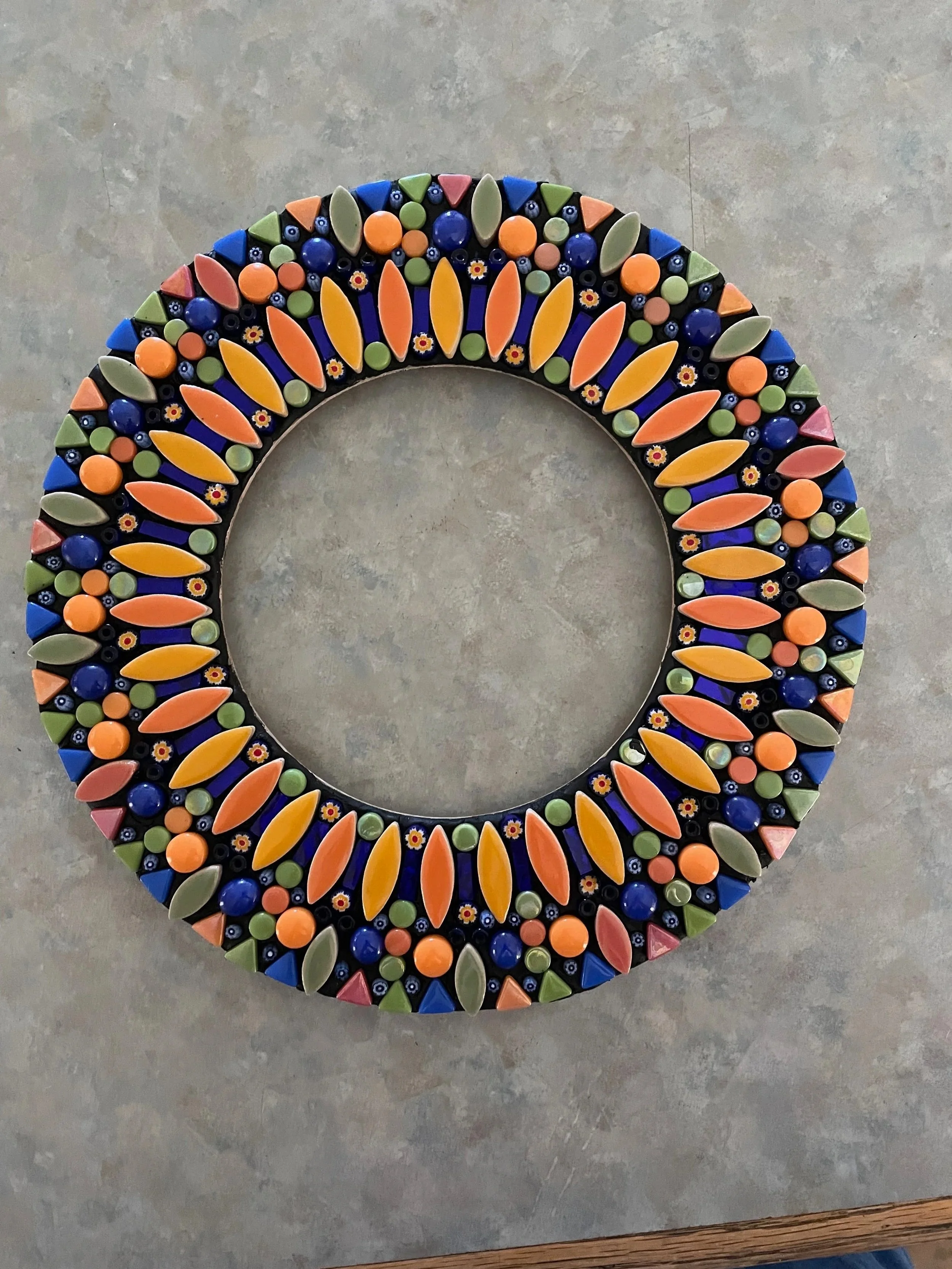 This 7 inch mosaic mirror is made with glass leaves, glass triangles, and glass dots.
