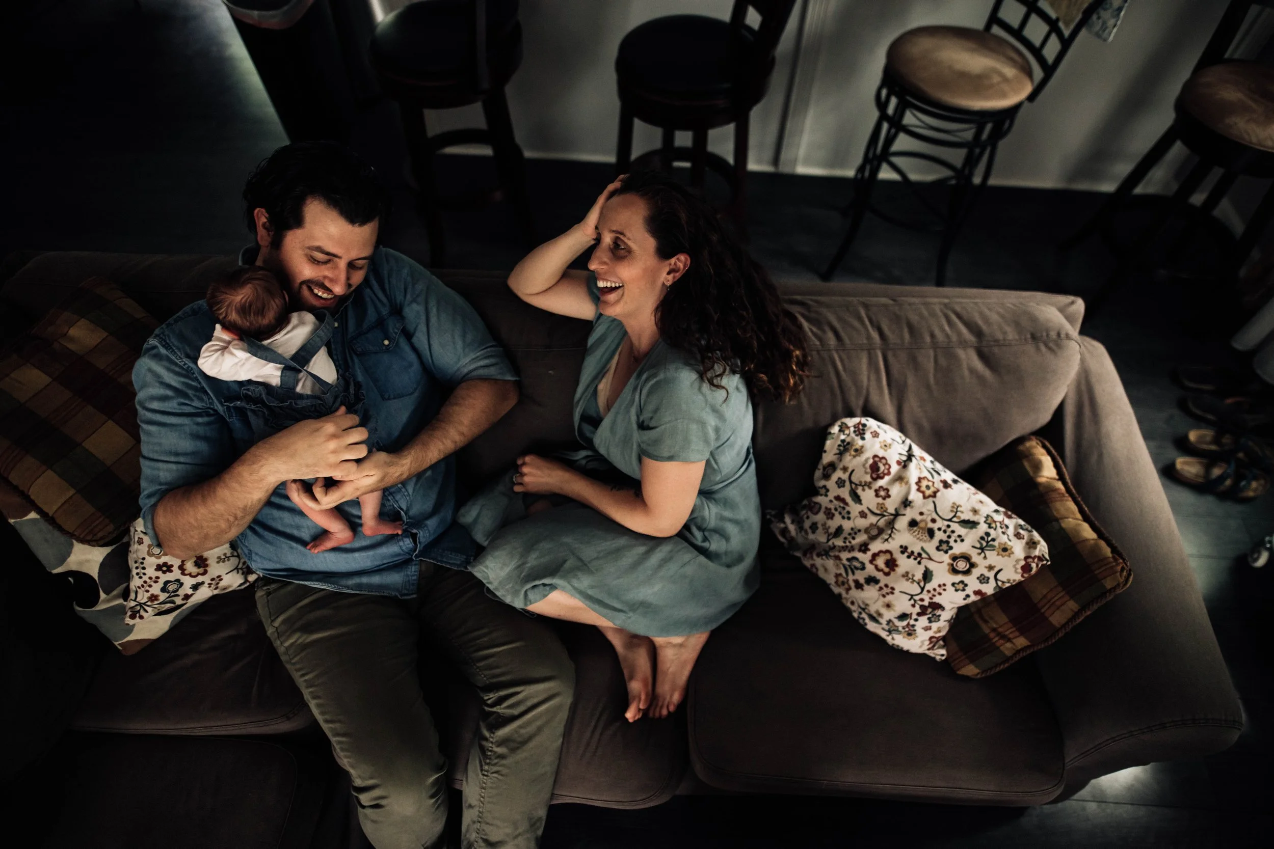 New mom and dad with their newborn on the couch at home
