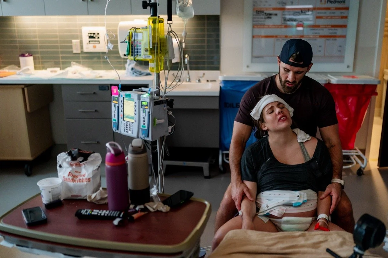Laboring woman sitting in front of her husband with a washcloth on her head