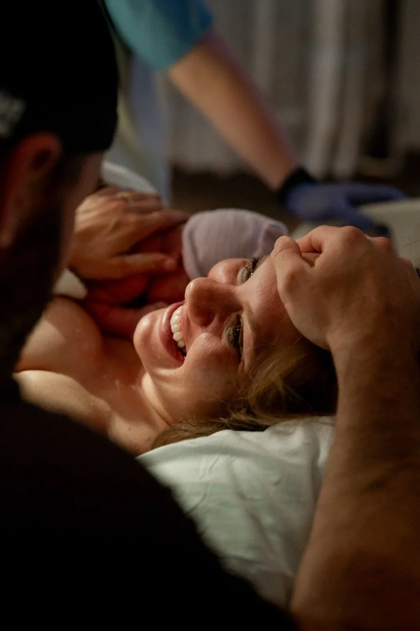 New mom smiling at new dad just after the birth of their baby