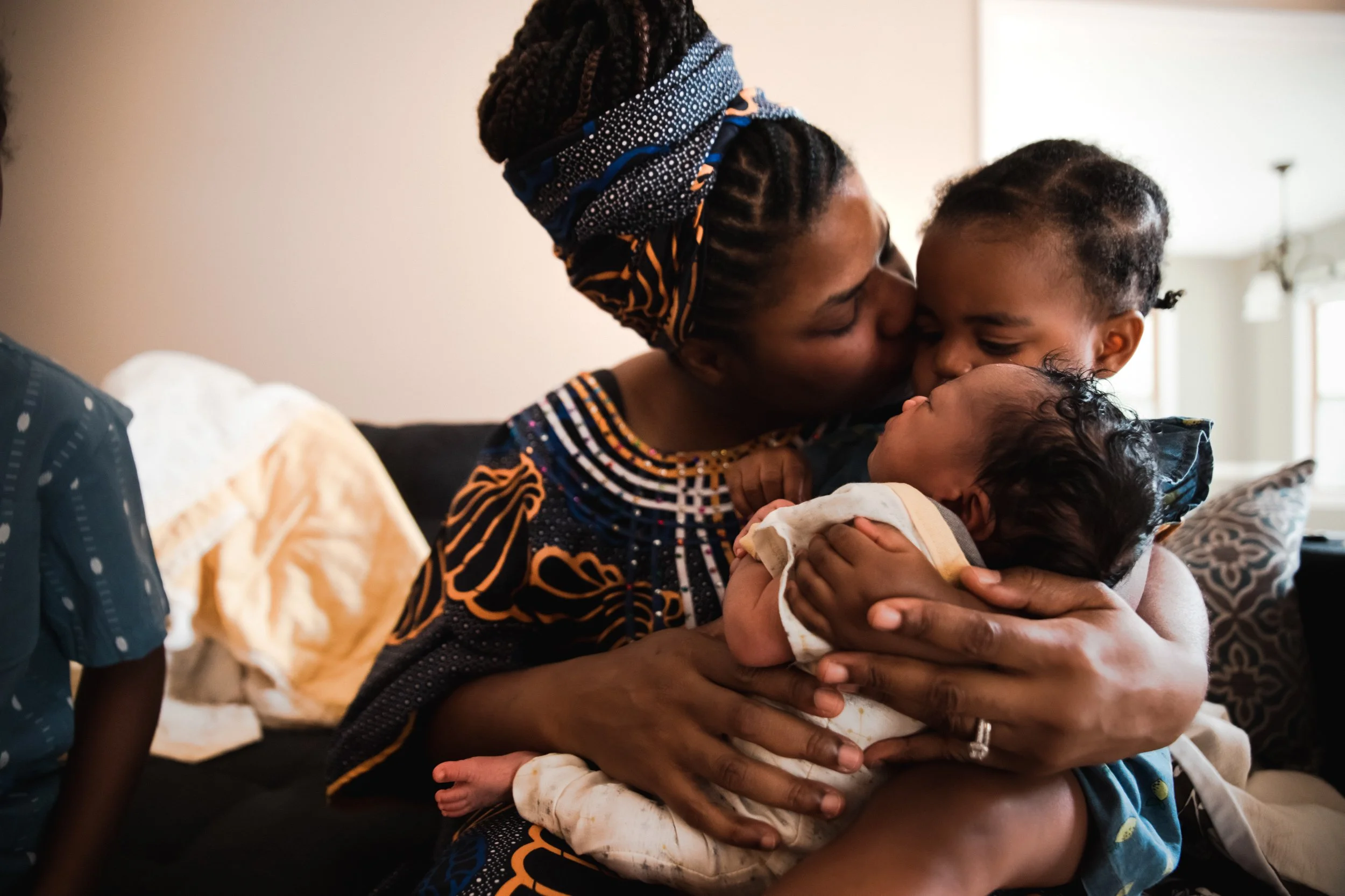 New Mother holding her baby and kissing her toddler