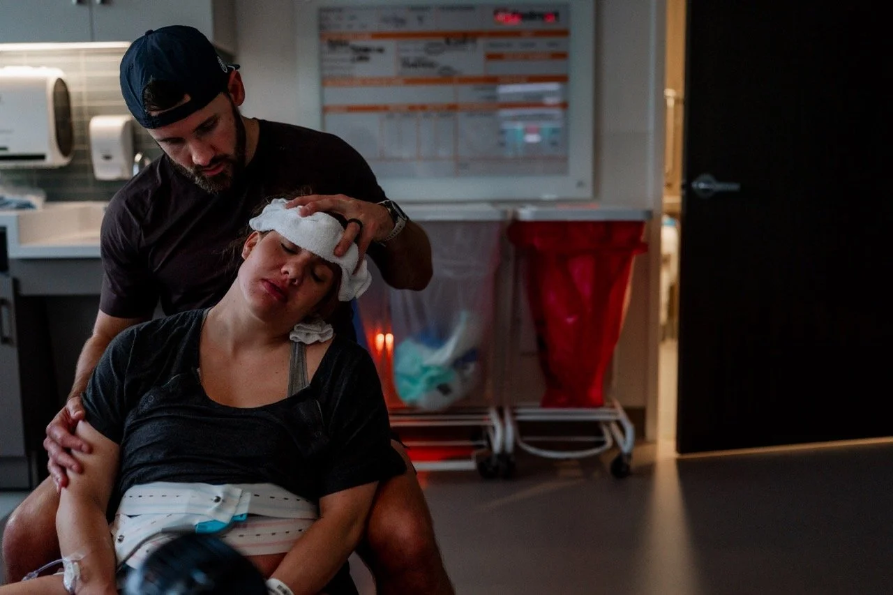 Man holding a washcloth on the forehead of a laboring woman at the hospital