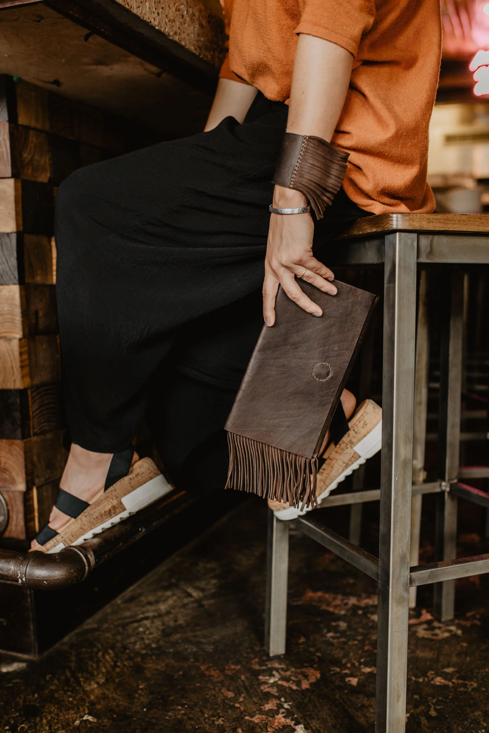brown leather clutch and leather bracelet with fringe