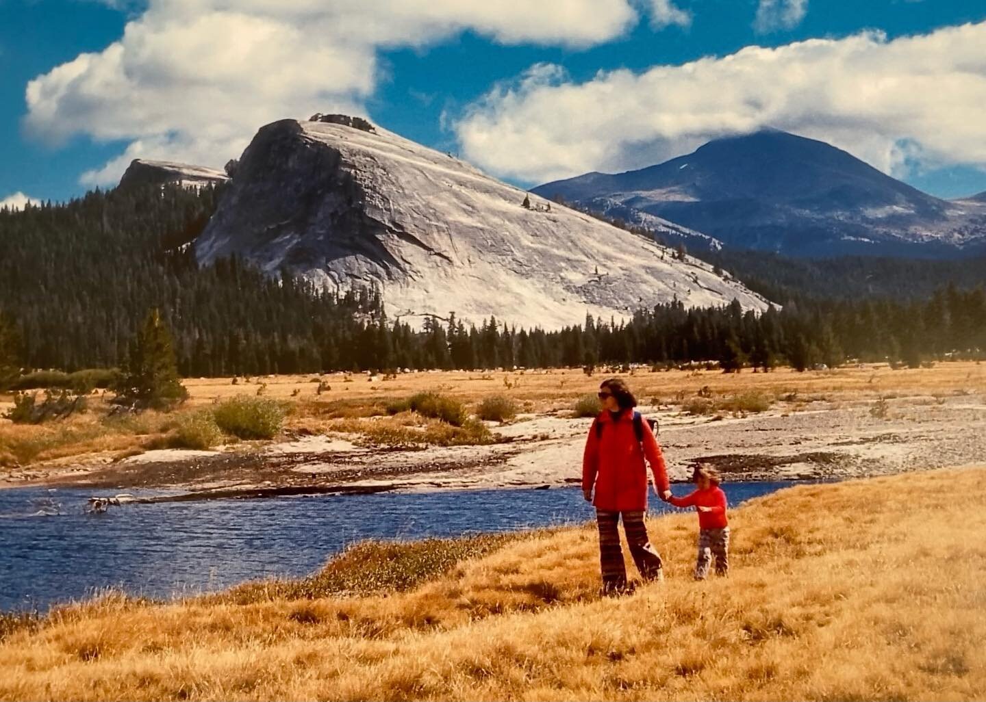 Image description: a woman in a red coat leading a little girl along a lake with mountains behind them.  My mama and me, 1973. Photo credit: Norman King 
I am holding a lot of complexity around the ways I feel about motherhood- as- construction. 
Any