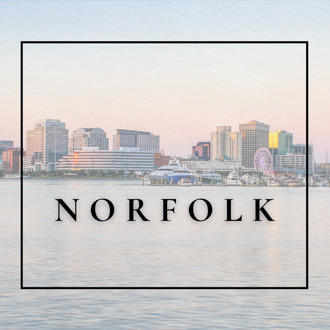 Waterfront city skyline of Norfolk, Virginia, with yachts docked in the harbor and a Ferris wheel in the background during sunset.