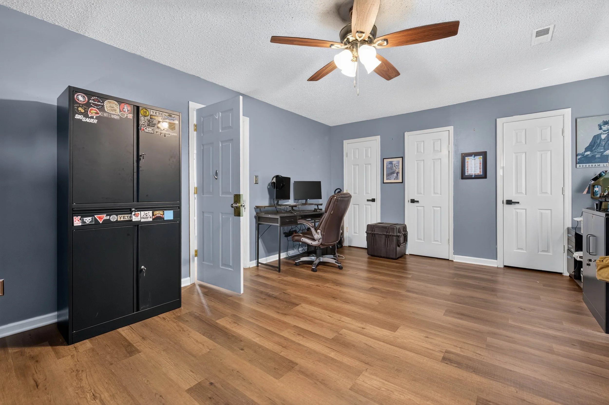 This upstairs bedroom has hardwood-style flooring, a ceiling fan and natural light.