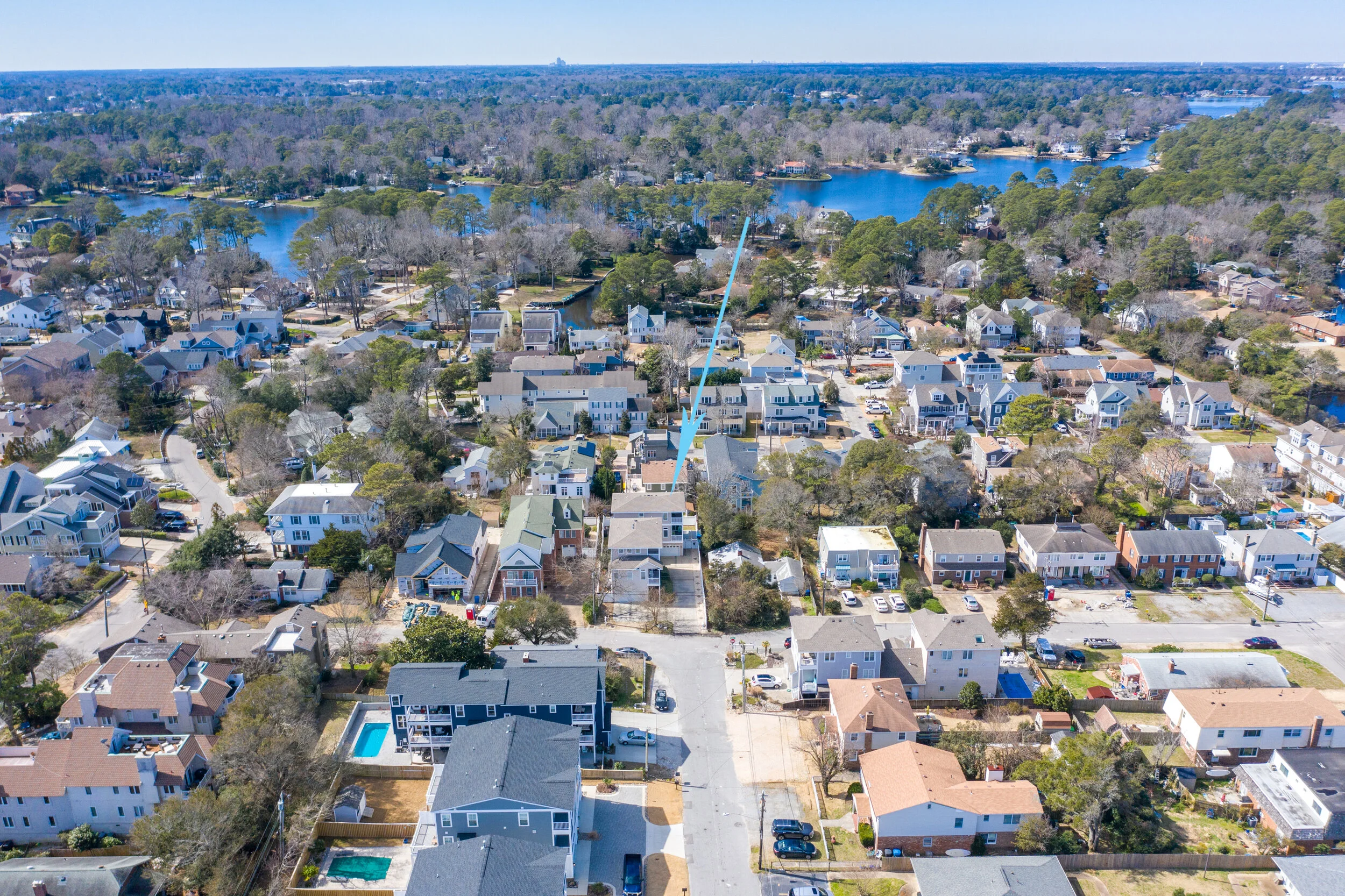 Aerial view of a residential neighborhood with diverse houses, a pool, and nearby trees and lakes.