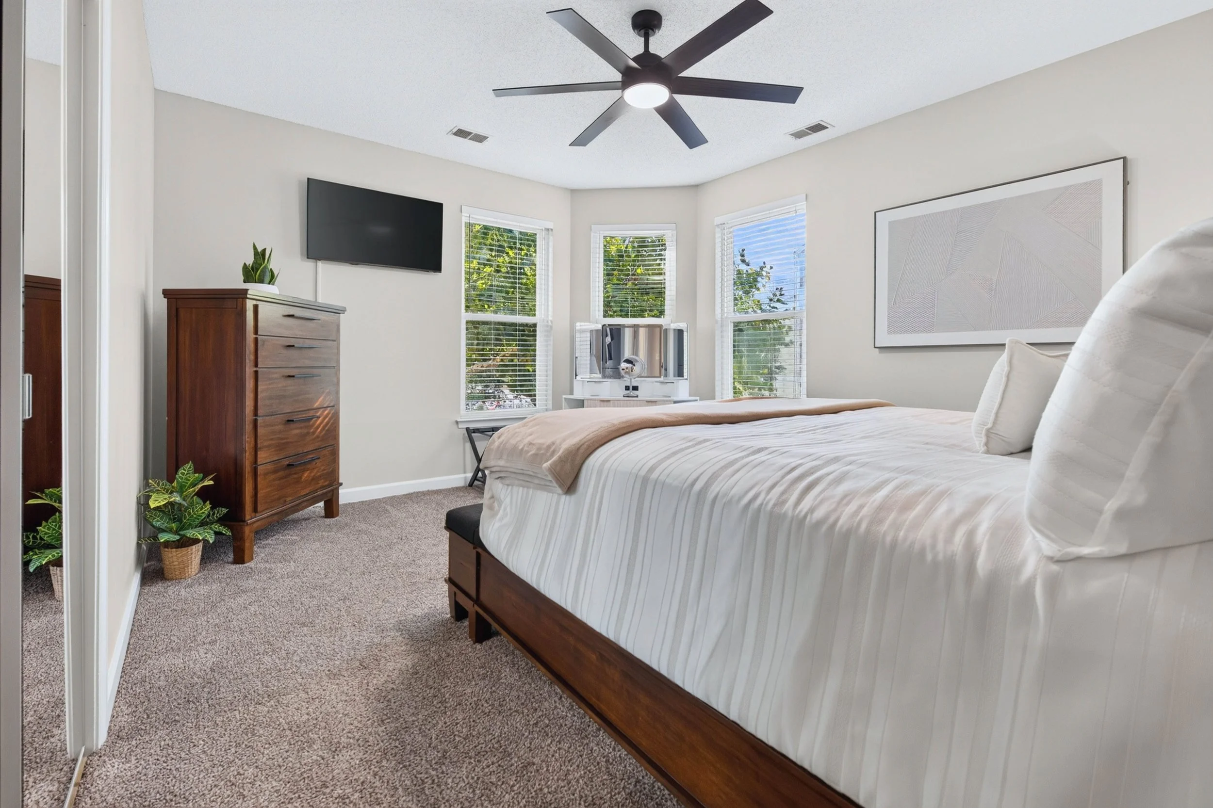Multiple windows fill the primary bedroom with natural light, creating a calm beginning and end to the day.