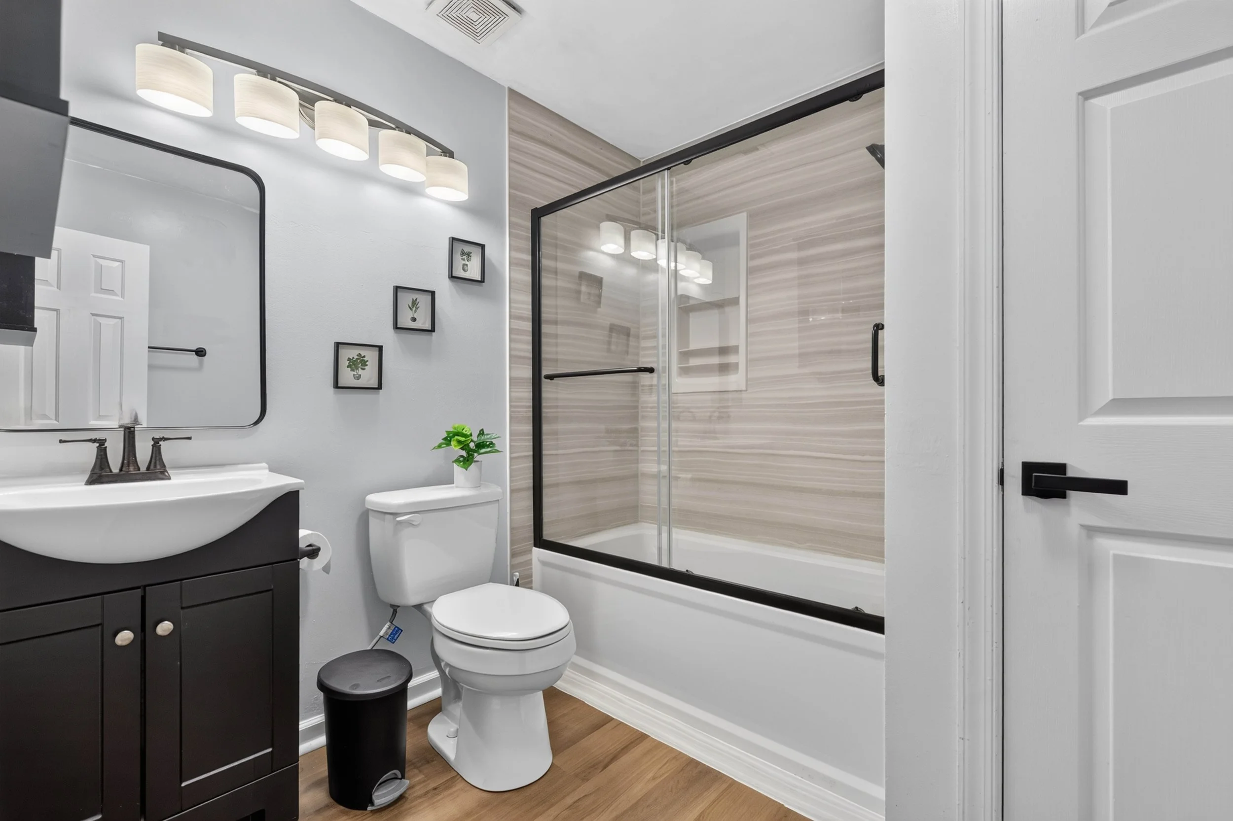 The upstairs full bathroom includes a dark vanity and a tub-shower combination with a glass enclosure.
