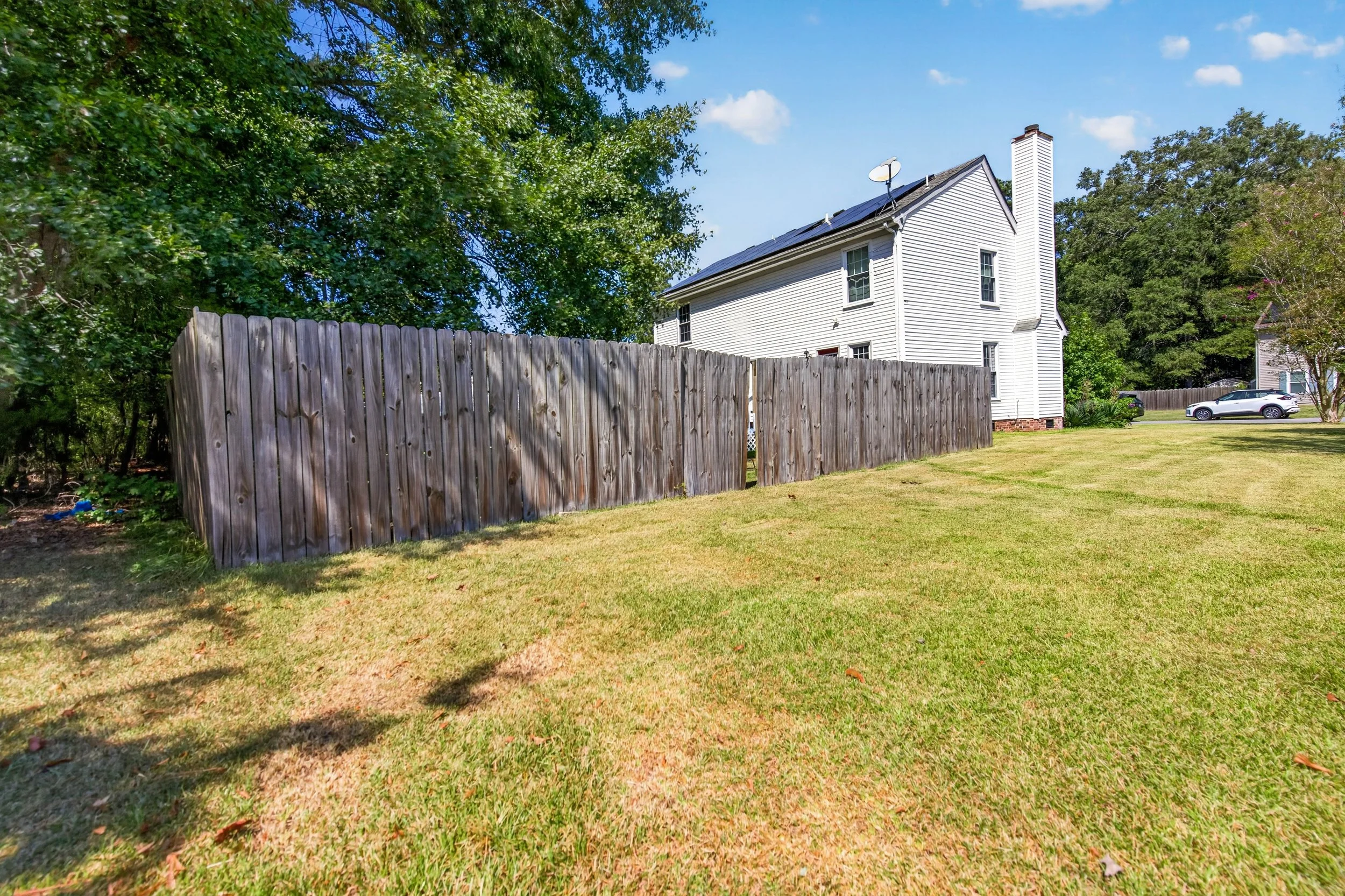 Open lawn extends between the rear deck and the side privacy fence.