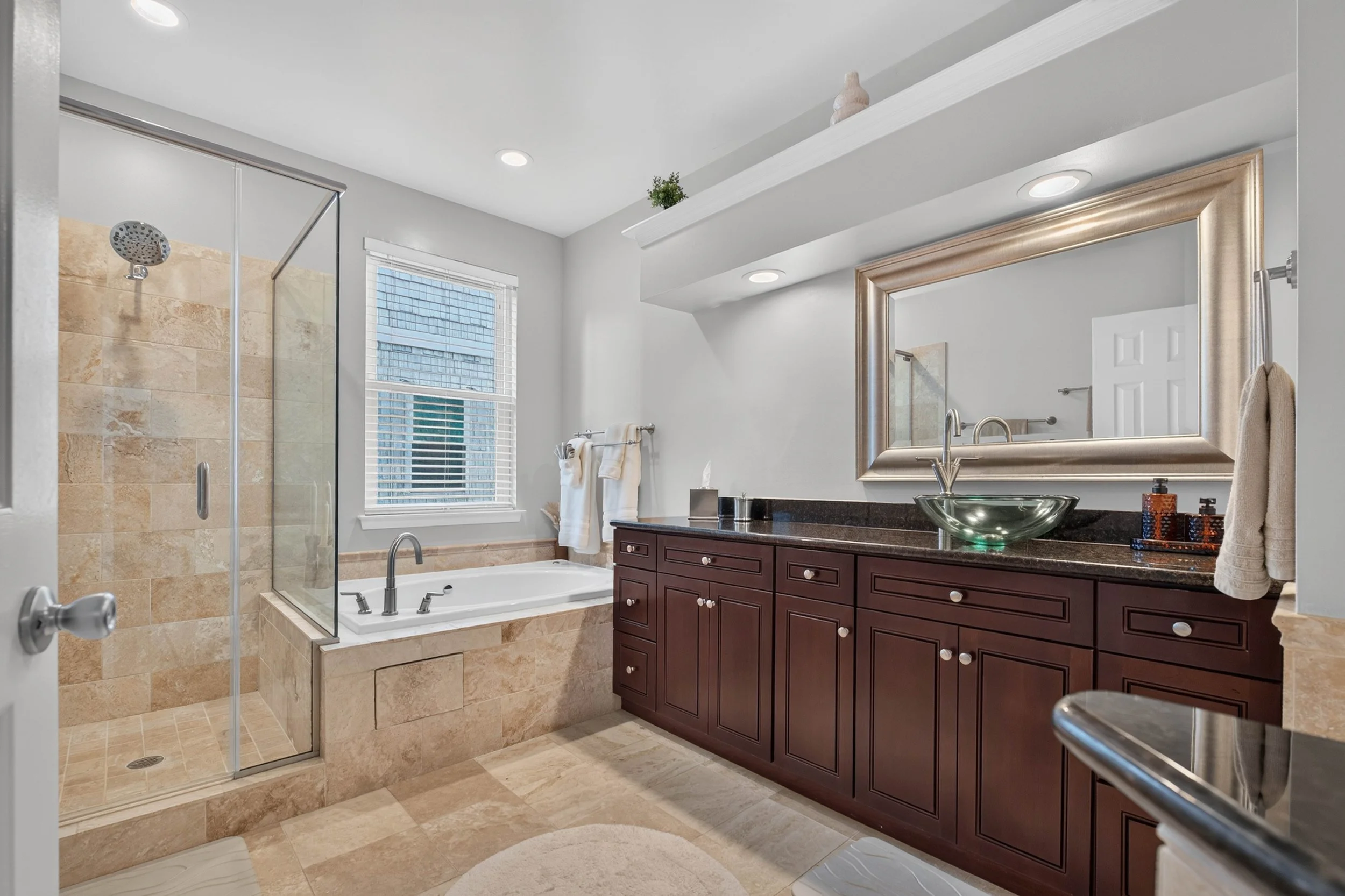 The renovated primary bath offers both a glass-enclosed shower and jetted tub for quick mornings or time to unwind.