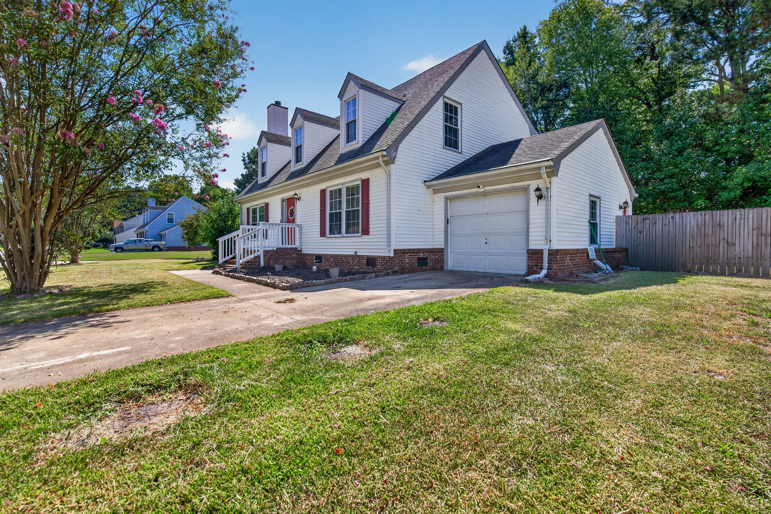 A side view shows the attached garage, driveway and corner-lot setting.