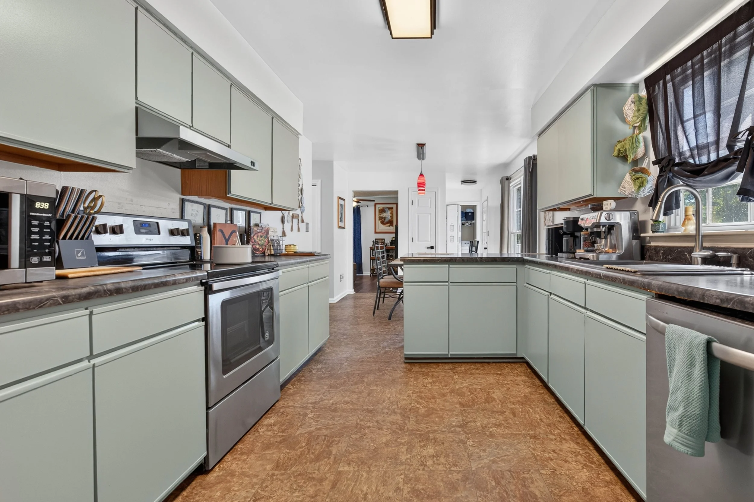 A full view of the kitchen shows the generous counter space, stainless appliances and connection to the dining area.