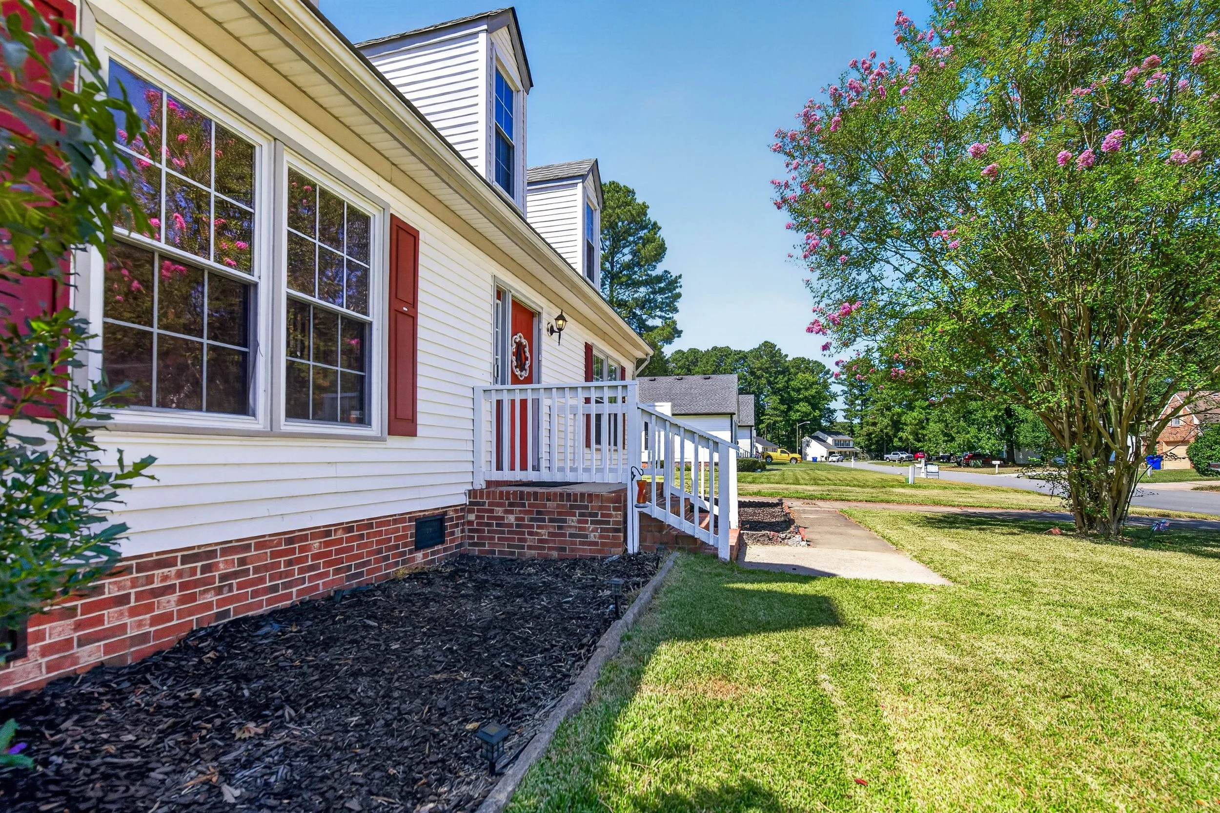Red shutters, a red entry door and established landscaping add definition to the front exterior.