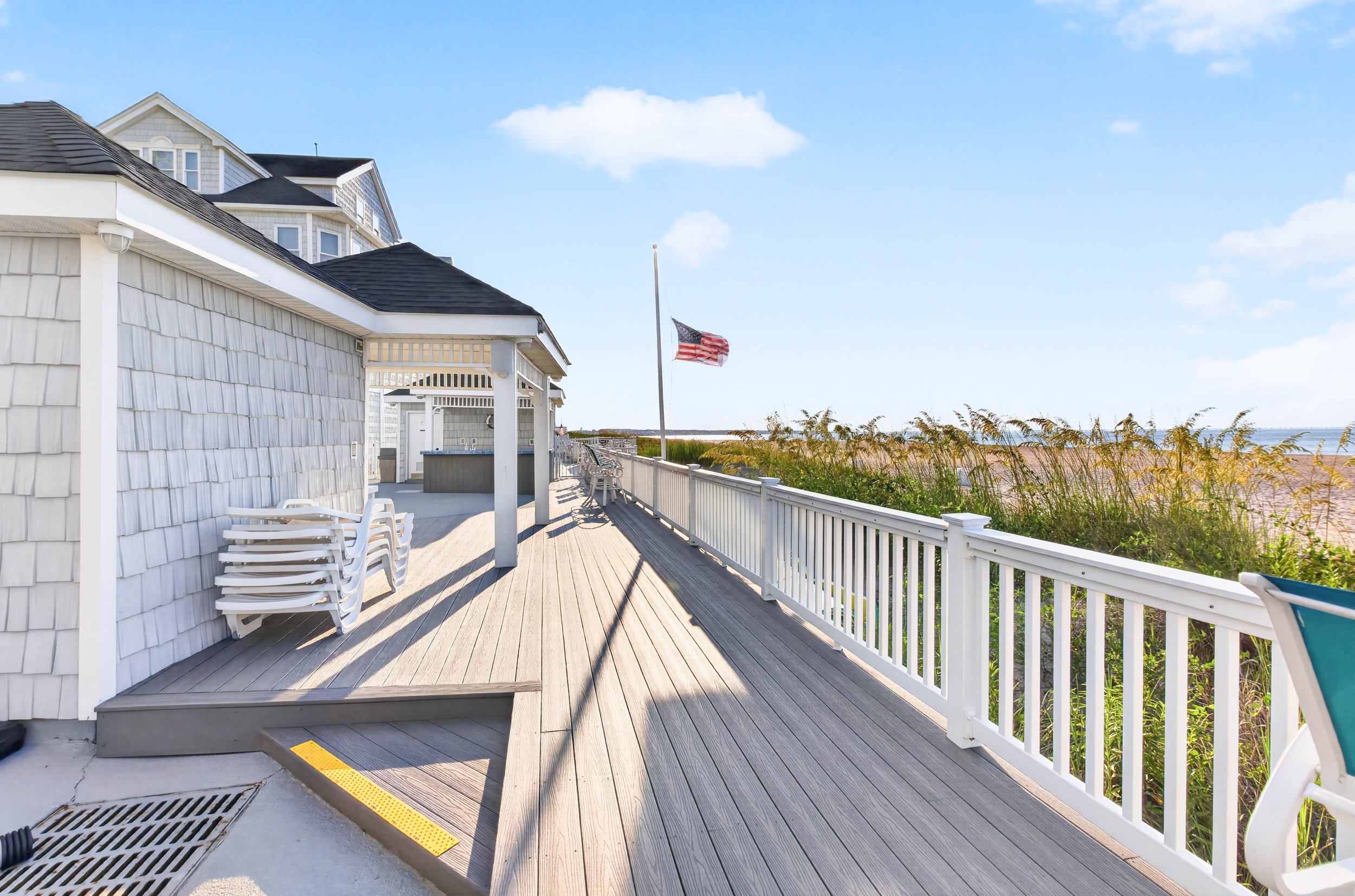 Composite decking connects the pool and gathering spaces, with direct beach access opening toward the Chesapeake Bay.